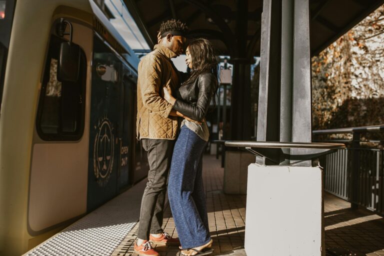 A couple shares a tender moment at a sunlit train station, symbolizing love and connection.