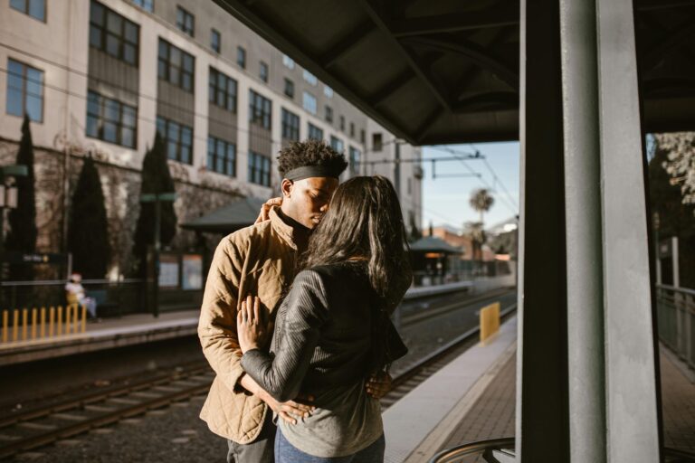 A loving couple sharing a moment at a train station in the city.